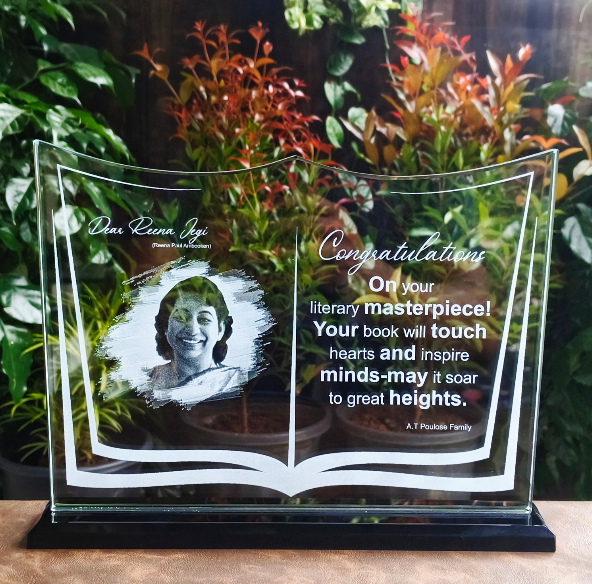 Glass award with engraved text and a photo of a person